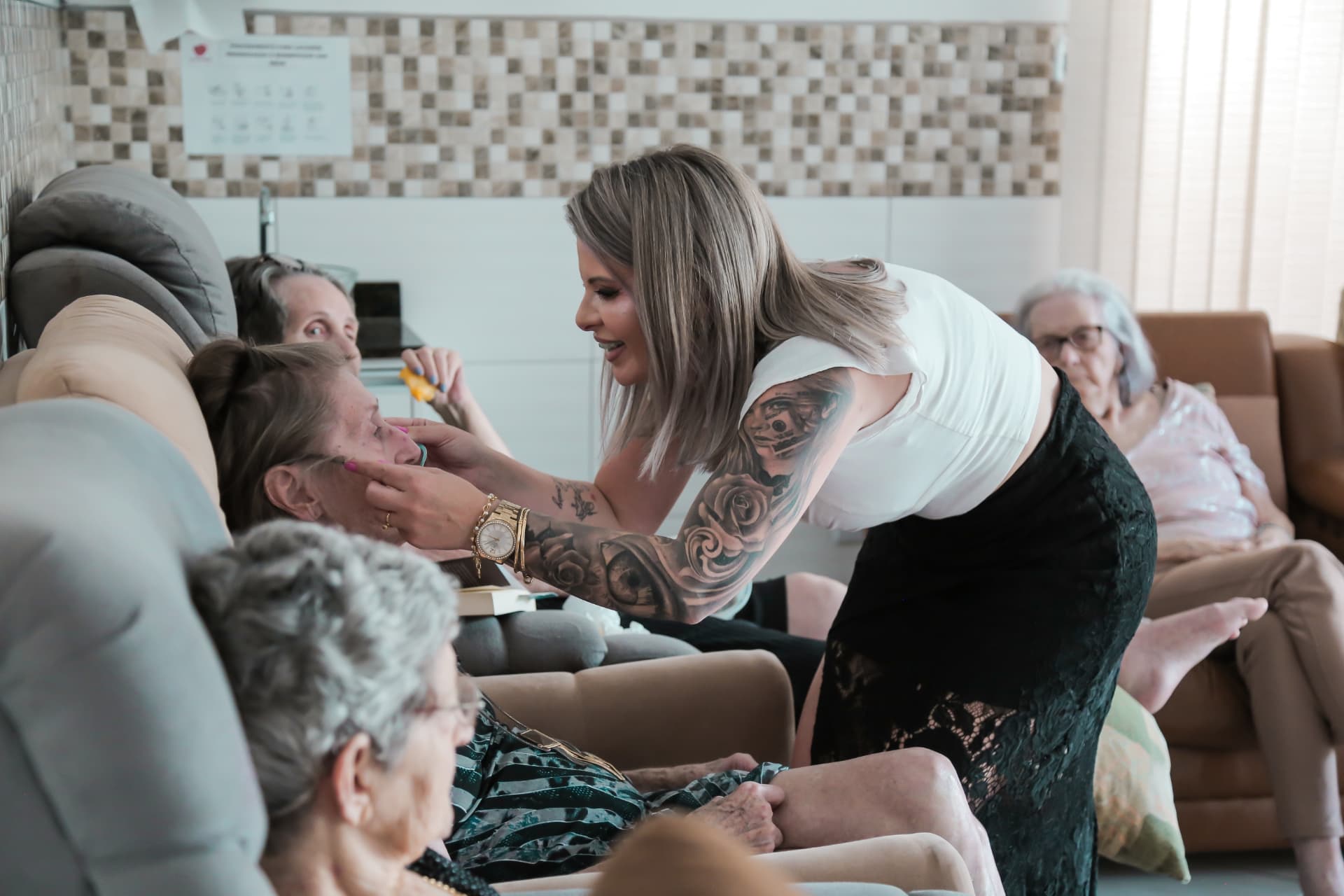 Profissional cuidando de residente idosa sentada em poltrona em uma das unidades da Aconchego Geriatria em Estância Velha/RS
